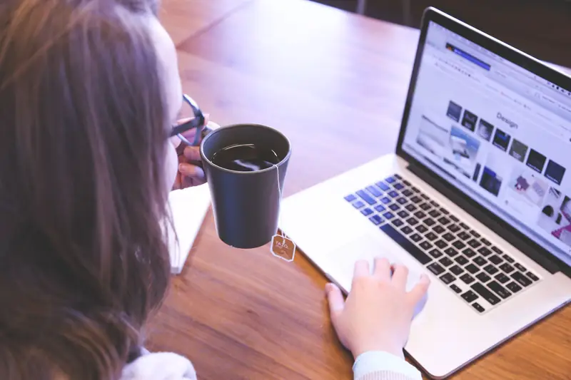 Persona trabajando desde su laptop con una taza de café
